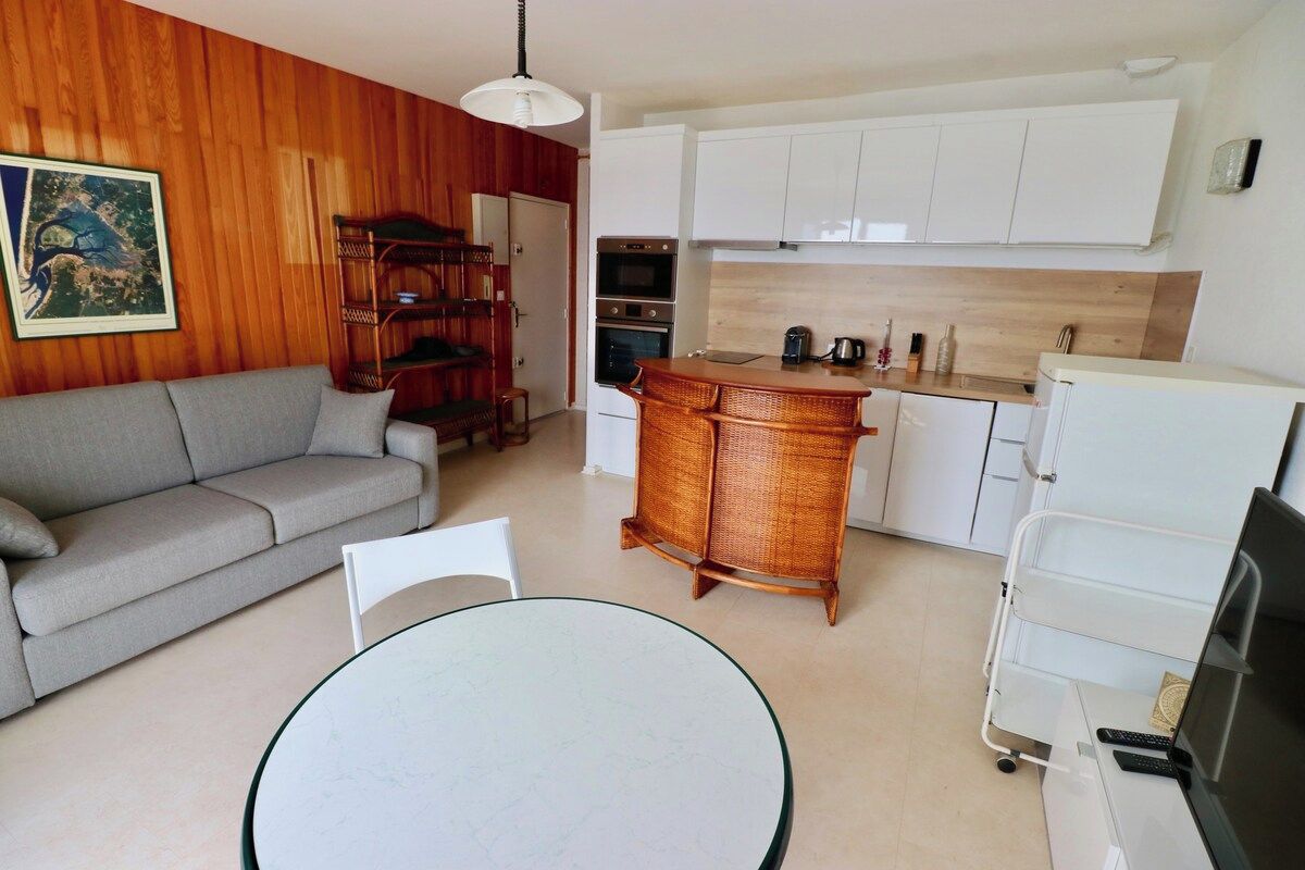 Una cucina moderna con mobili bianchi, un'area pranzo con un tavolo rotondo e un divano.