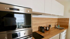 A modern kitchen with stainless steel appliances, a wooden countertop, and a view of the sea. - Studio in top location, 1st line on the bay with fantastic bay view and Wifi (Lège-Cap-Ferret)
