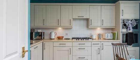 A modern kitchen with white cabinets, a gas stove, a microwave, and a toaster.