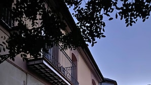 A two-story building with a stone facade, a balcony with a wrought iron railing, and a traditional wooden door. - Room-magnolia Loft A Spacious, Authent (Alzira)