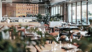 A modern restaurant interior with a bar area, dining tables, chairs, and large windows. - Nickel Resort & Wellnest Grzybowo (Grzybowo)