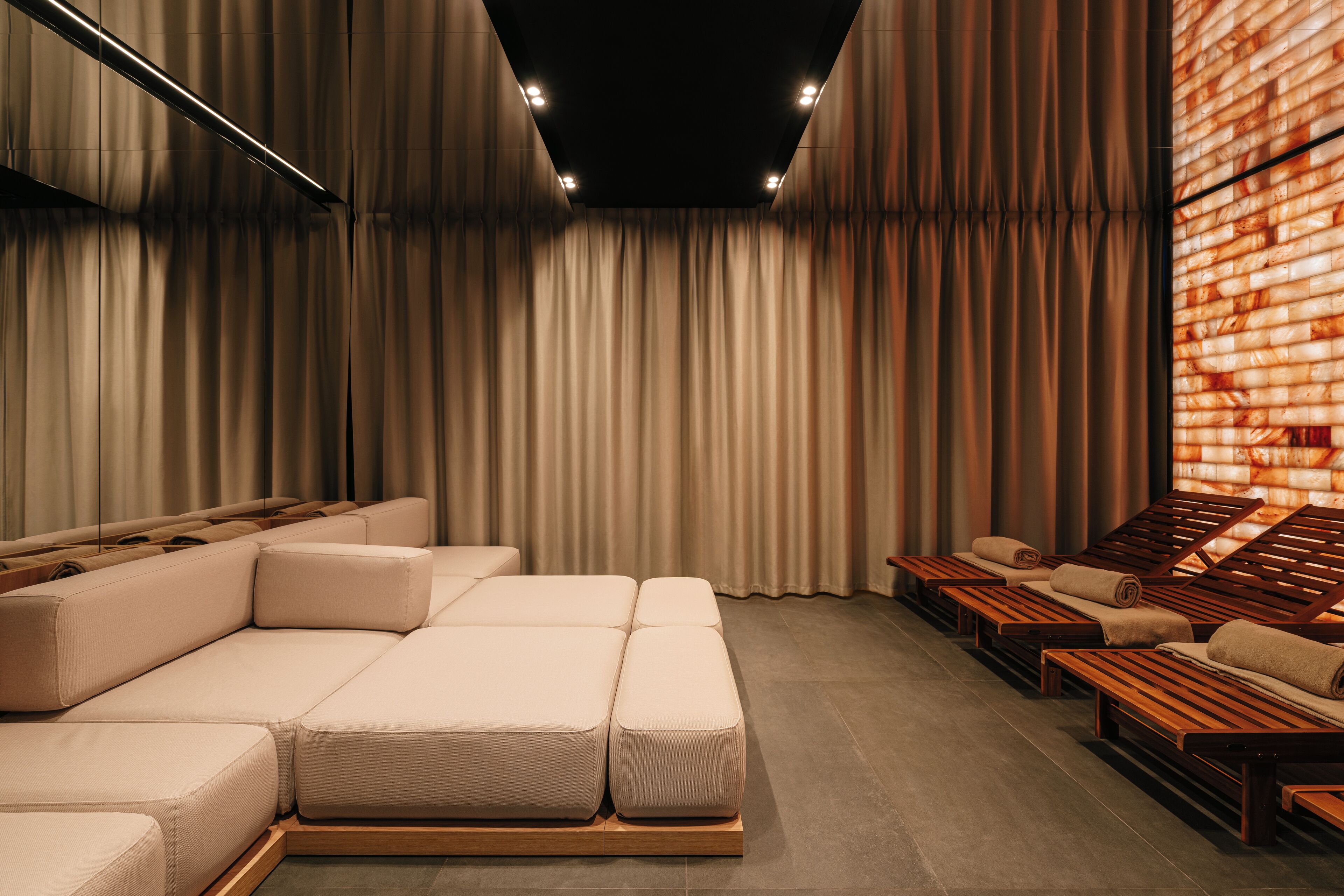 Una habitación moderna y bien iluminada con un amplio sofá modular y sillones de madera.