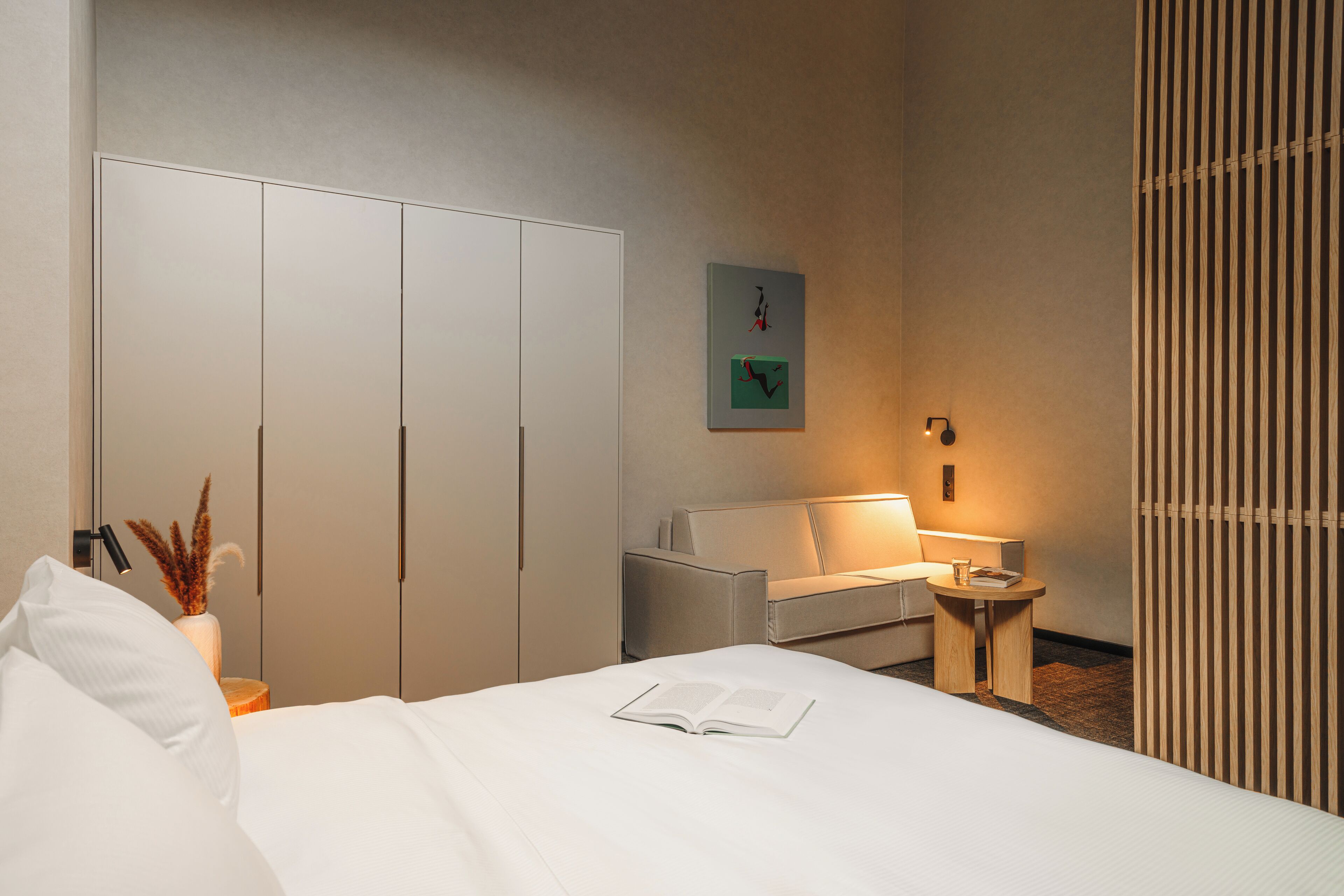 Une chambre d’hôtel avec un lit, un canapé, une petite table, une lampe et une armoire.