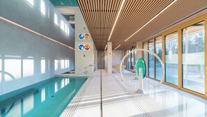 A modern indoor swimming pool with clear signage, a wooden ceiling, and large windows. - Nickel Resort & Wellnest Grzybowo (Grzybowo)
