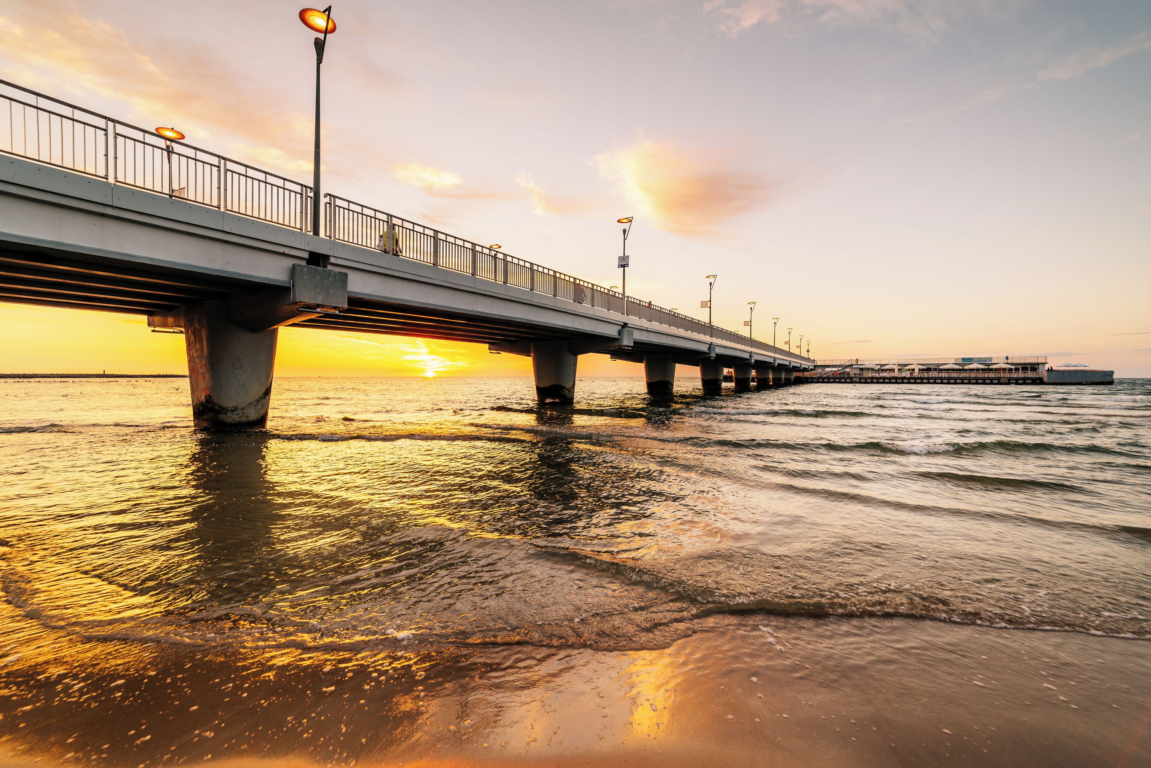 Un pont éclairé par des lampadaires, avec un coucher de soleil en arrière-plan.