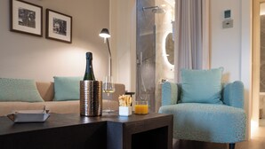 A modern living room with a sofa, a coffee table, and a glass shower enclosure. - Anna Teresa Luxury (Pisa)
