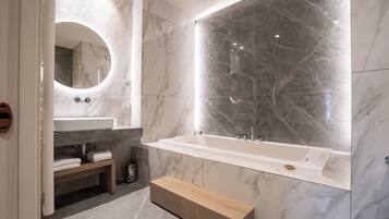 Ein modernes Badezimmer mit Marmorwaschtisch, freistehender Badewanne und einer Holzbank.