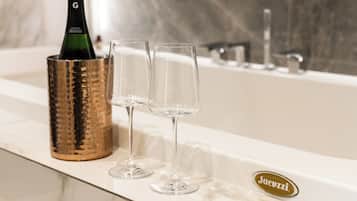 A champagne bottle in a gold holder next to two glasses on a bathroom counter.