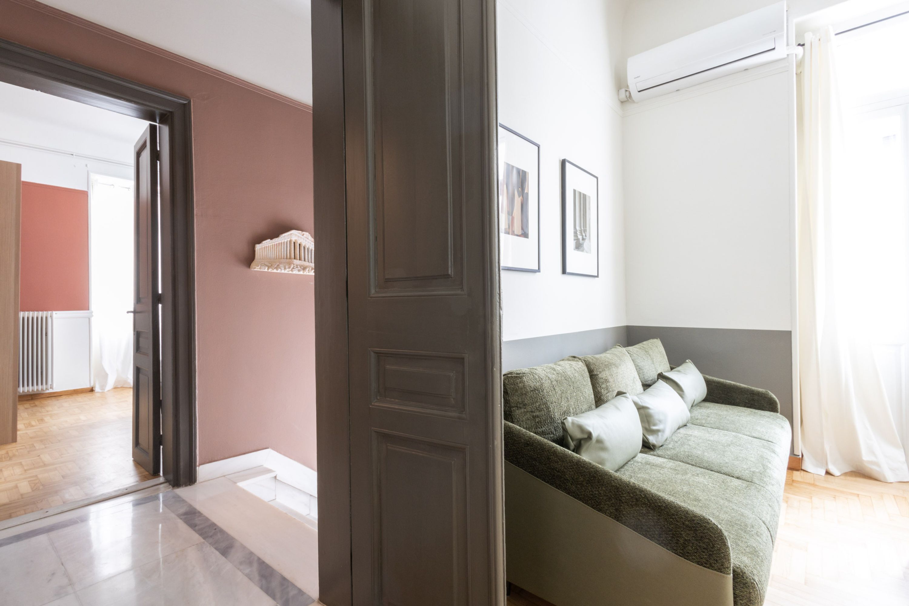 A modern living room with a sofa, a door, and framed pictures on the wall.