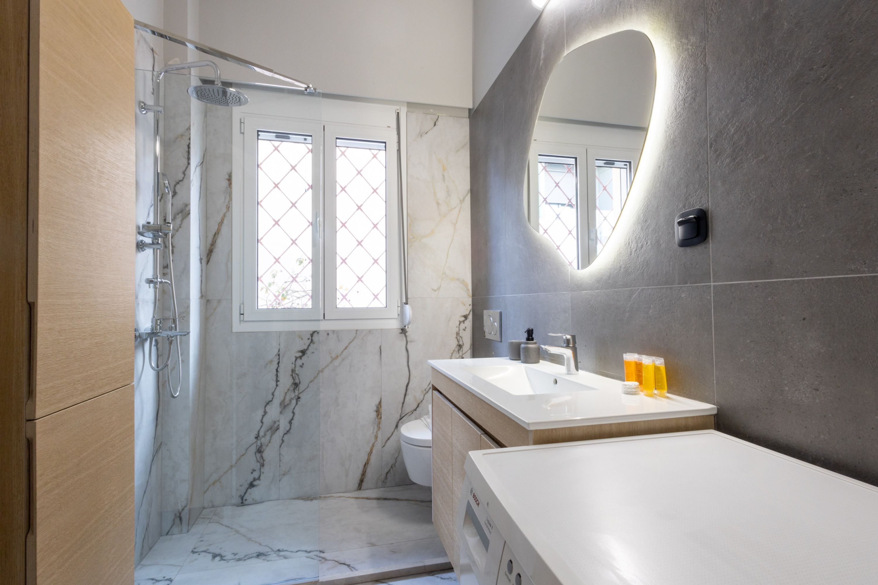 A modern bathroom with a shower, toilet, and sink.