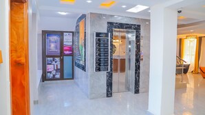 Vestíbulo de hotel con piso de mármol, una mesa de recepción y un letrero con los números de habitación y sus pisos correspondientes.