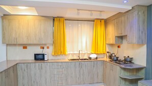 Una cocina moderna con armarios de madera, microondas, pileta y estufa a gas.