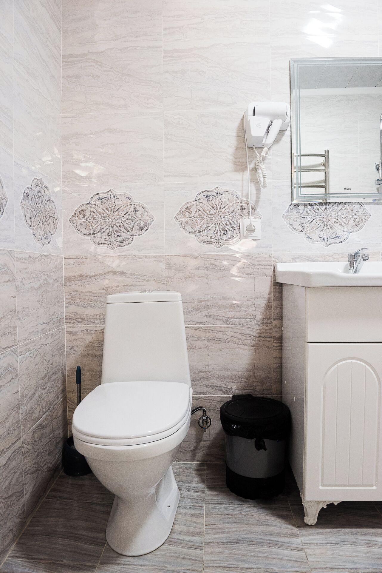 A bathroom with a toilet, a sink, and a hairdryer mounted on the wall.