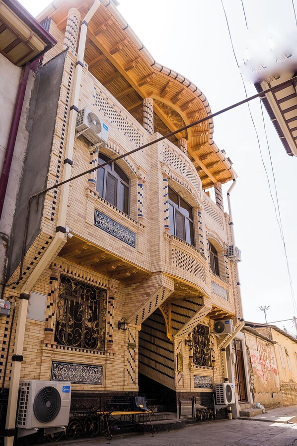 Un edificio de varios pisos con una fachada distintiva a cuadros, balcones y unidades de aire acondicionado.