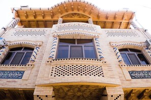 Un edificio con un estilo arquitectónico distintivo que presenta ventanas arqueadas, detalles intrincados en mosaico y un balcón de madera.