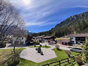 A village with traditional houses, a paved central area, and mountains in the background.