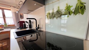 A modern kitchen with a black countertop, stainless steel sink, and a black range hood. - Fewo Sonnenglück - dreamlike 2-room apartment for 1-2 persons with corner balcony (Schönau am Königssee)