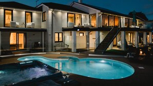 Une maison moderne à deux étages, dotée d’une piscine, d’un espace salon extérieur et d’un escalier menant à l’étage supérieur.