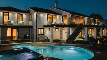 A modern two-story house with a swimming pool, outdoor seating, and a staircase leading to the upper floor.