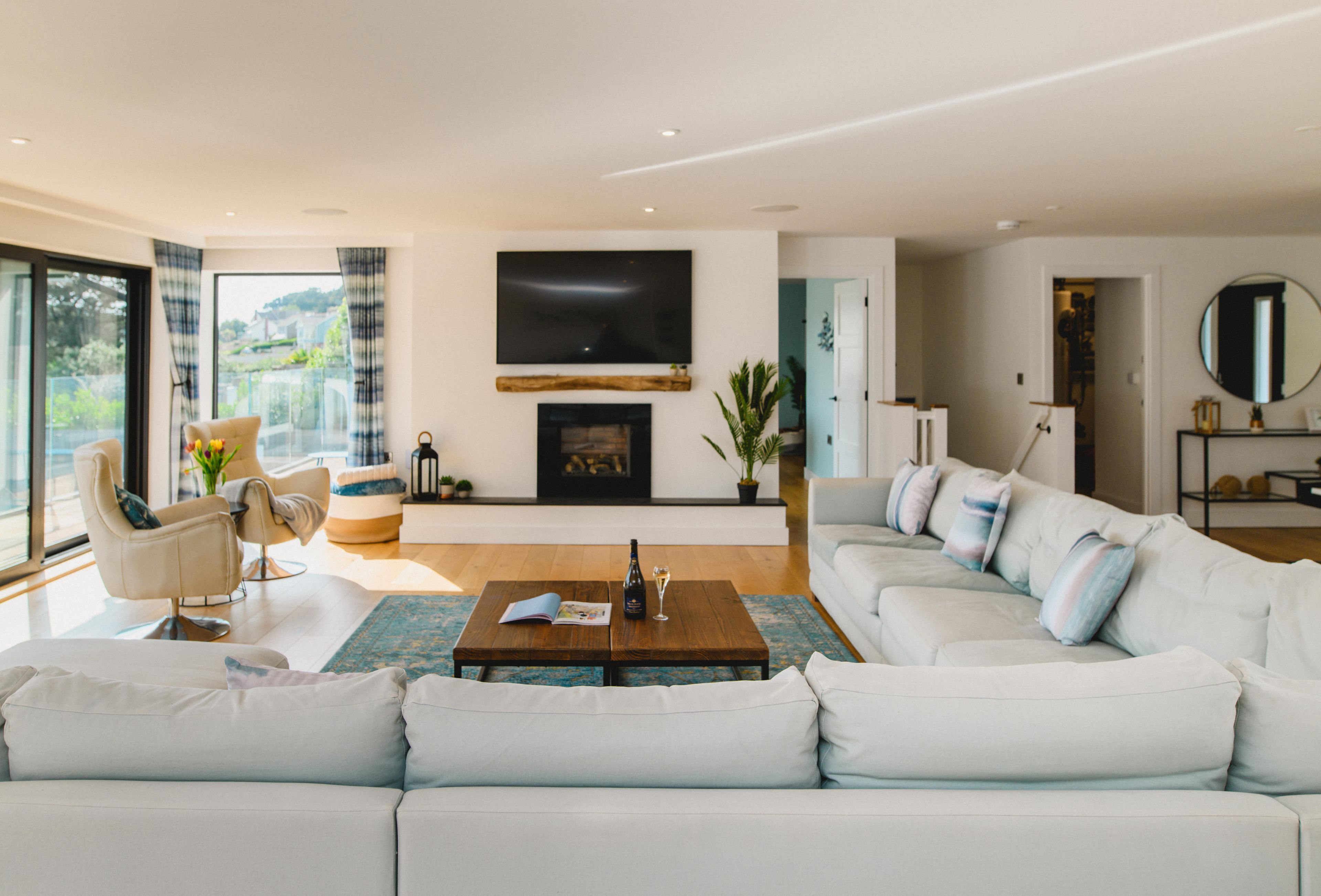 A modern living room with a large sectional sofa, a coffee table, a fireplace, and a television.