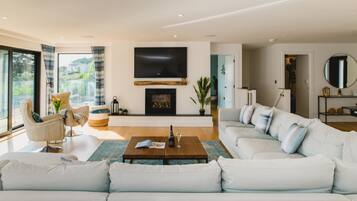 A modern living room with a large sectional sofa, a coffee table, a fireplace, and a television.