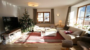 Un salon chaleureux avec un sapin de Noël, un canapé, une table basse et un téléviseur.