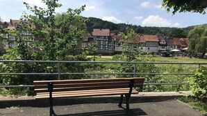A bench in a park with a view of traditional buildings and a hill in the background. - Holiday Home 'Am Fulda Ufer' with Wi-Fi (Rotenburg an der Fulda)