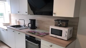 A modern kitchen with a built-in oven, a microwave, a coffee maker, and a sink. - Holiday Home 'Am Fulda Ufer' with Wi-Fi (Rotenburg an der Fulda)