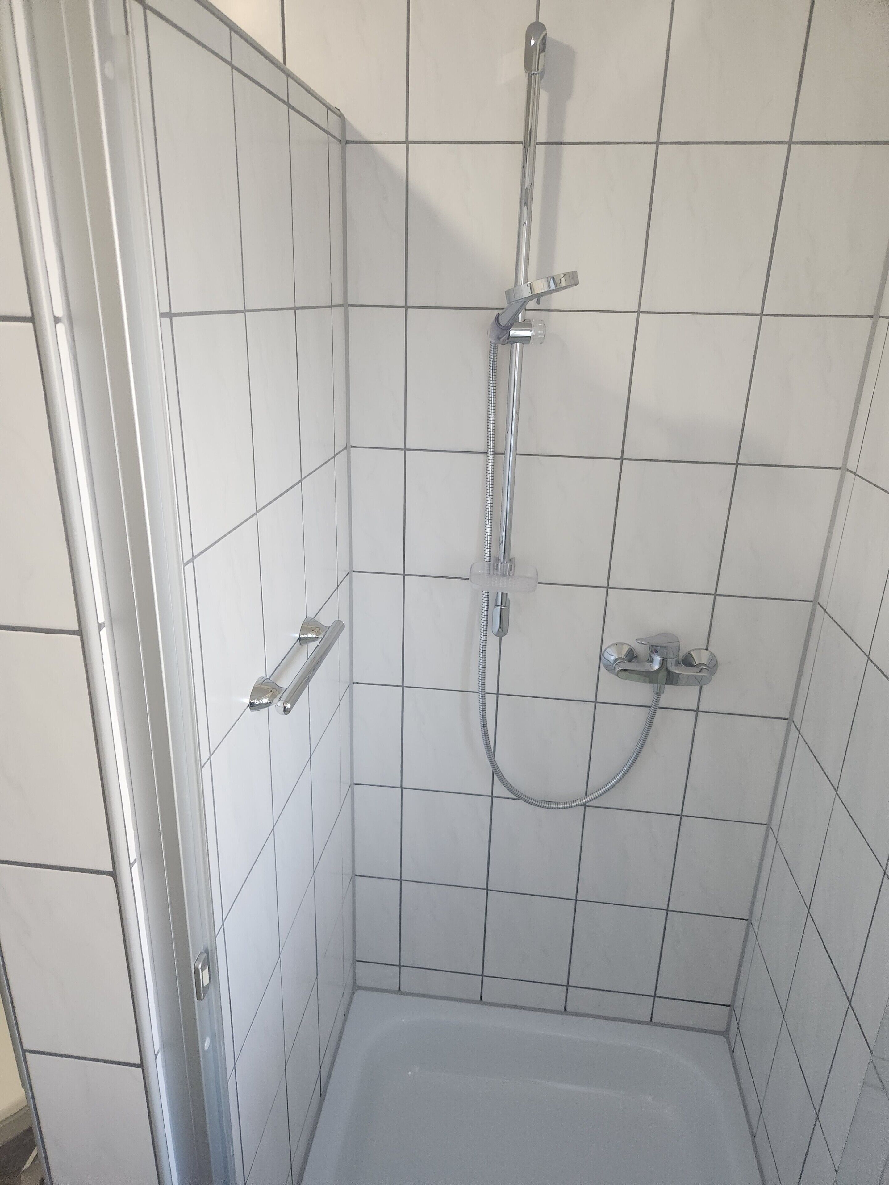 Un espace douche équipé d’un pommeau de douche à main, d’un robinet mural et d’une baignoire.