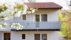 A two-story house with a balcony, a door, and a garden. - Holiday Apartment 'Riesling' with Private Balcony, Shared Terrace (Iphofen)