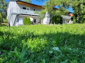 Rakennuksessa on parveke, portaikko ja nurmialue, jossa kasvaa kukkia.