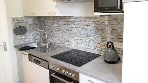 A kitchen with a stone backsplash, stainless steel appliances, and a kettle. - Holiday Apartment 'Riesling' with Private Balcony, Shared Terrace (Iphofen)