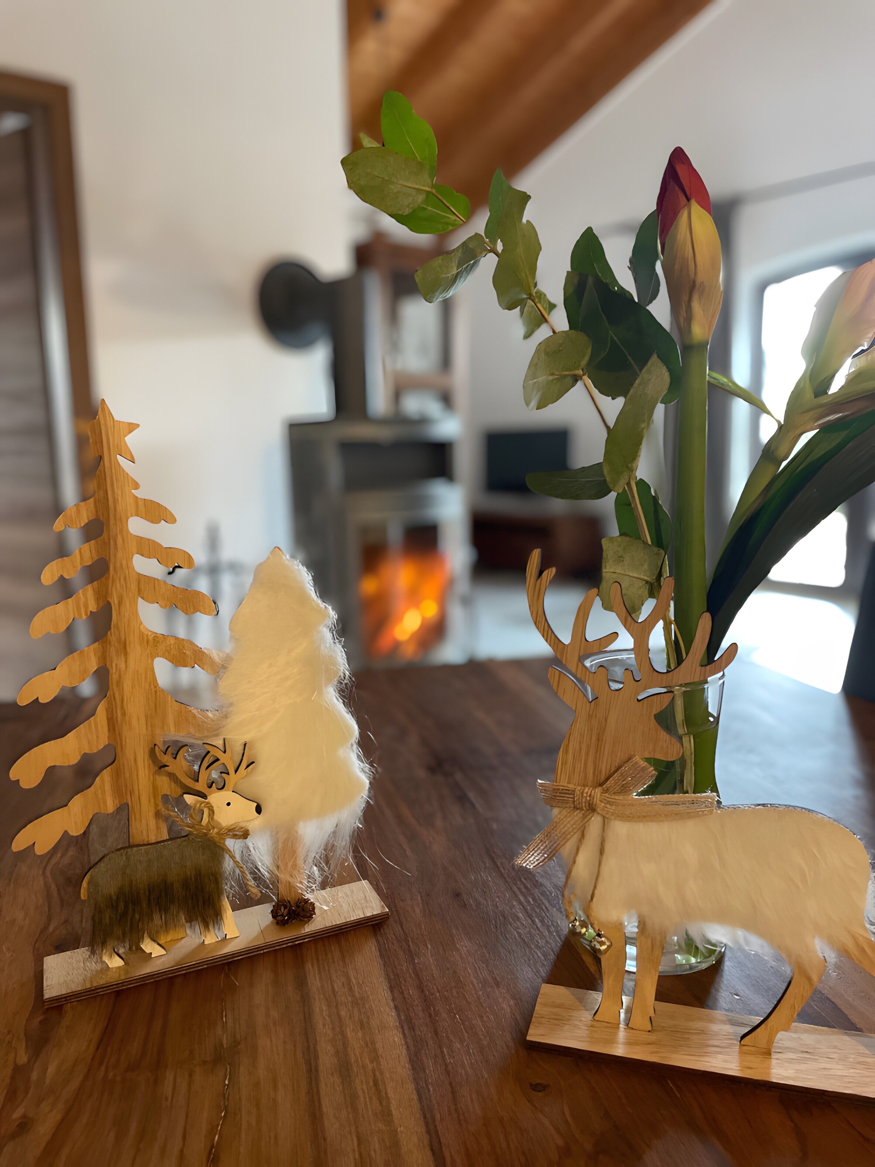 Ein Holztisch mit einer dekorativen Anordnung, darunter ein Baum, eine weiße, flauschige Skulptur und eine Hirschfigur.