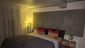 Un dormitorio con cama, mesitas de noche y un buró.