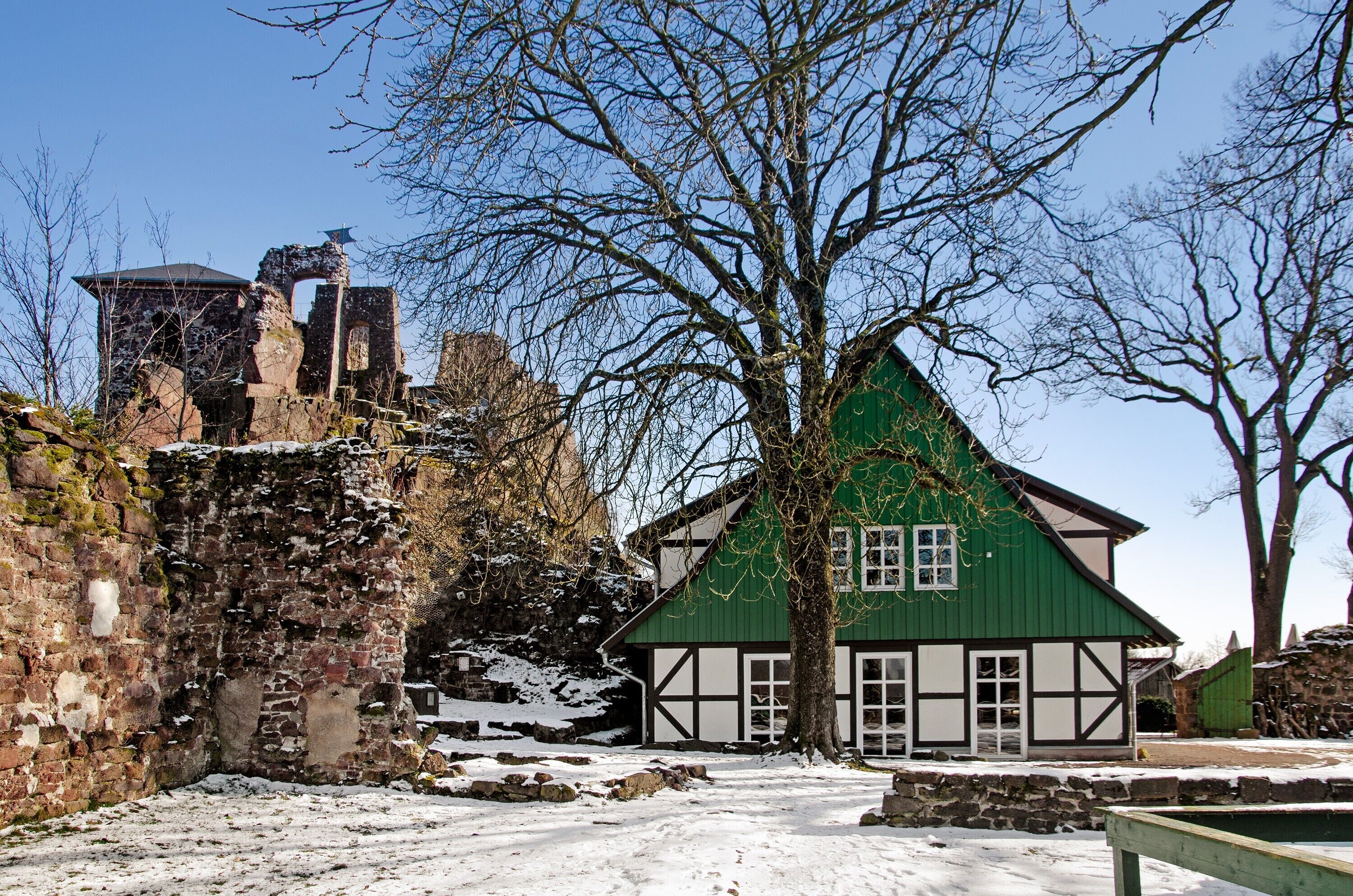 Een historisch gebouw met een groen dak en witte details, omgeven door sneeuw.