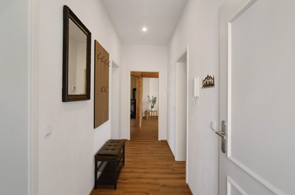 Un pasillo con suelo de madera, un banco y una puerta con pomo.