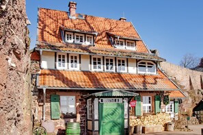 A two-story building with a tiled roof, a green door, and a sign indicating a restaurant.