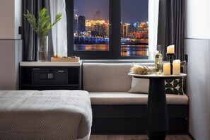 Habitación de hotel con cama, sofá, una mesita con velas, una botella y un jarrón con plantas.