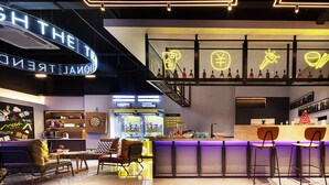 A modern bar area with neon signs, a counter, and seating.