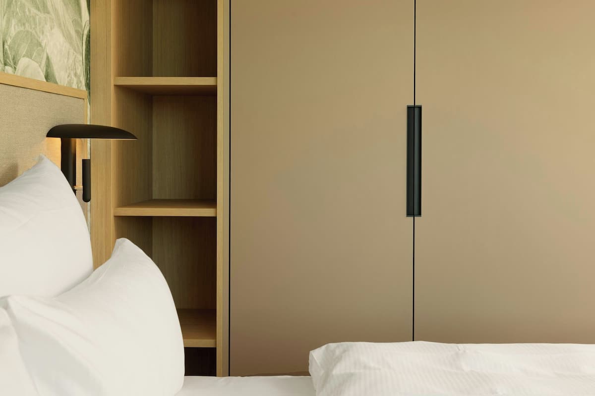 A bedroom with a bed, a wardrobe, and a nightstand with a lamp.