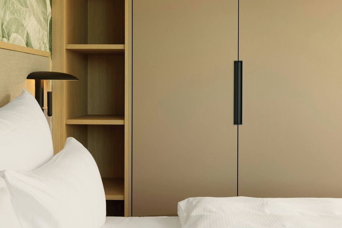 Un dormitorio con cama, armario y mesita de noche con lámpara.