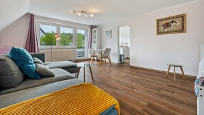 A modern living room with a sofa, a small table, and a dining area. - Studio Apartment 'Ruhiges Apartment' with Balcony and Wi-Fi (Horn-Bad Meinberg)