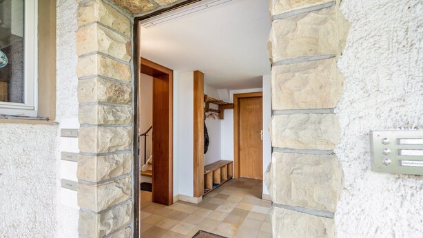 A stone-walled hallway with a wooden door, a bench, and a coat rack. - Studio Apartment 'Ruhiges Apartment' with Balcony and Wi-Fi (Horn-Bad Meinberg)
