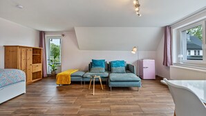 A modern living room with a sofa, a wooden cabinet, a small table, and a window with curtains. - Studio Apartment 'Ruhiges Apartment' with Balcony and Wi-Fi (Horn-Bad Meinberg)