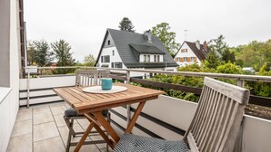 A balcony with a wooden table and chairs, a view of houses, and a railing. - Studio Apartment 'Ruhiges Apartment' with Balcony and Wi-Fi (Horn-Bad Meinberg)