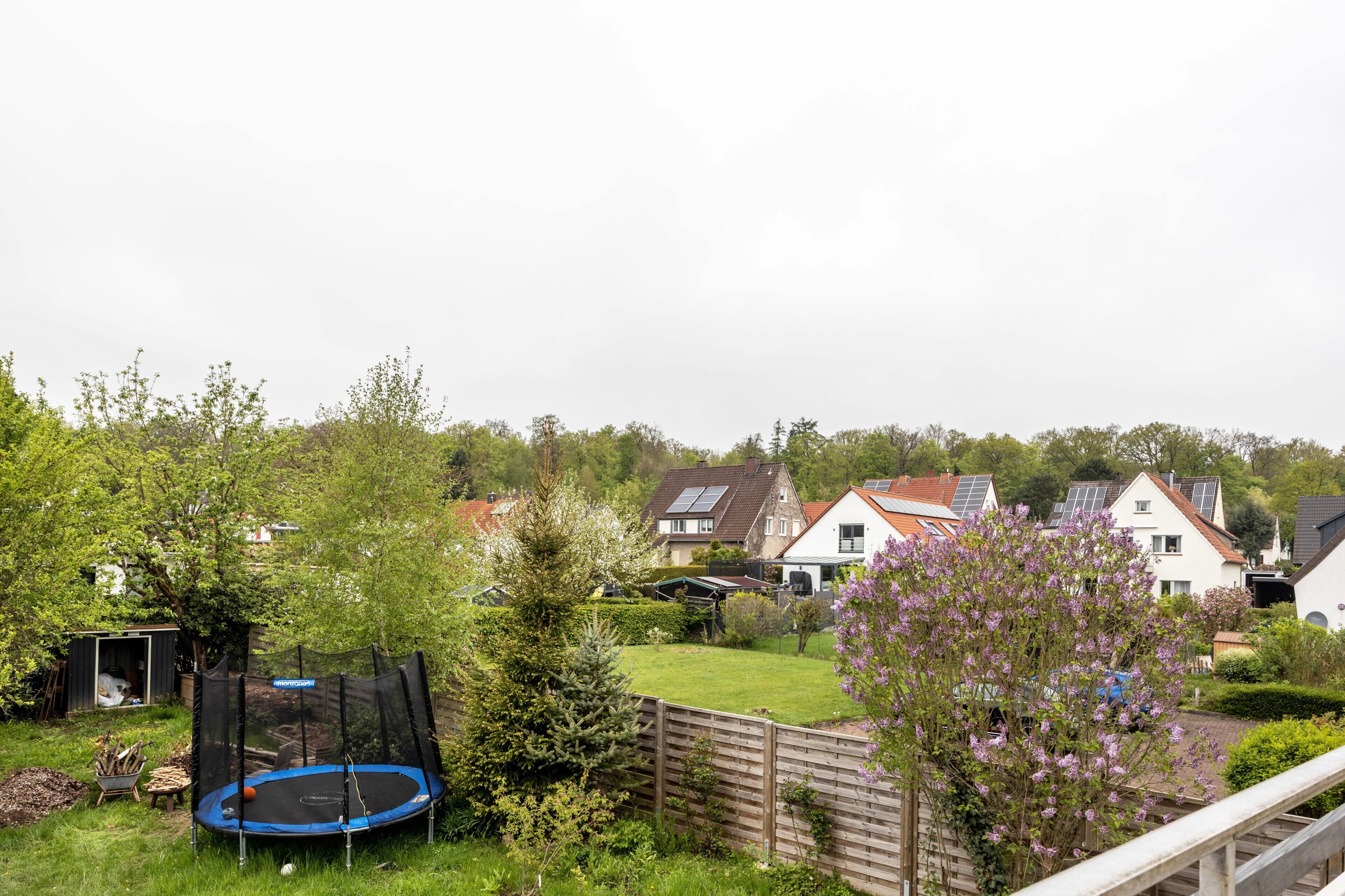 Un quartier résidentiel avec des maisons, un trampoline et une clôture en bois.