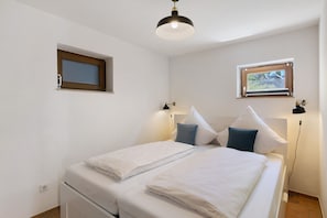 A bedroom with a bed, two bedside tables, a window, and a ceiling light.