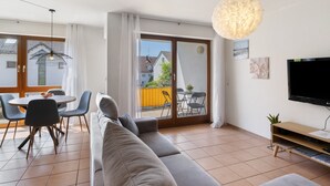 A modern living room with a sofa, dining table, chairs, and a TV. - Apartment 'Seeside' with Lake View, Balcony and Wi-Fi (Uhldingen-Mühlhofen)