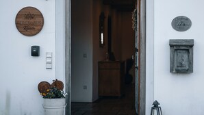 A building entrance with a wooden door, a wall-mounted light, and a sign with the name 'FERIENHAUS Kaiser'. - Holiday Home 'Kaiser' with Mountain View, Private Terrace and Wi-Fi (Aßling)