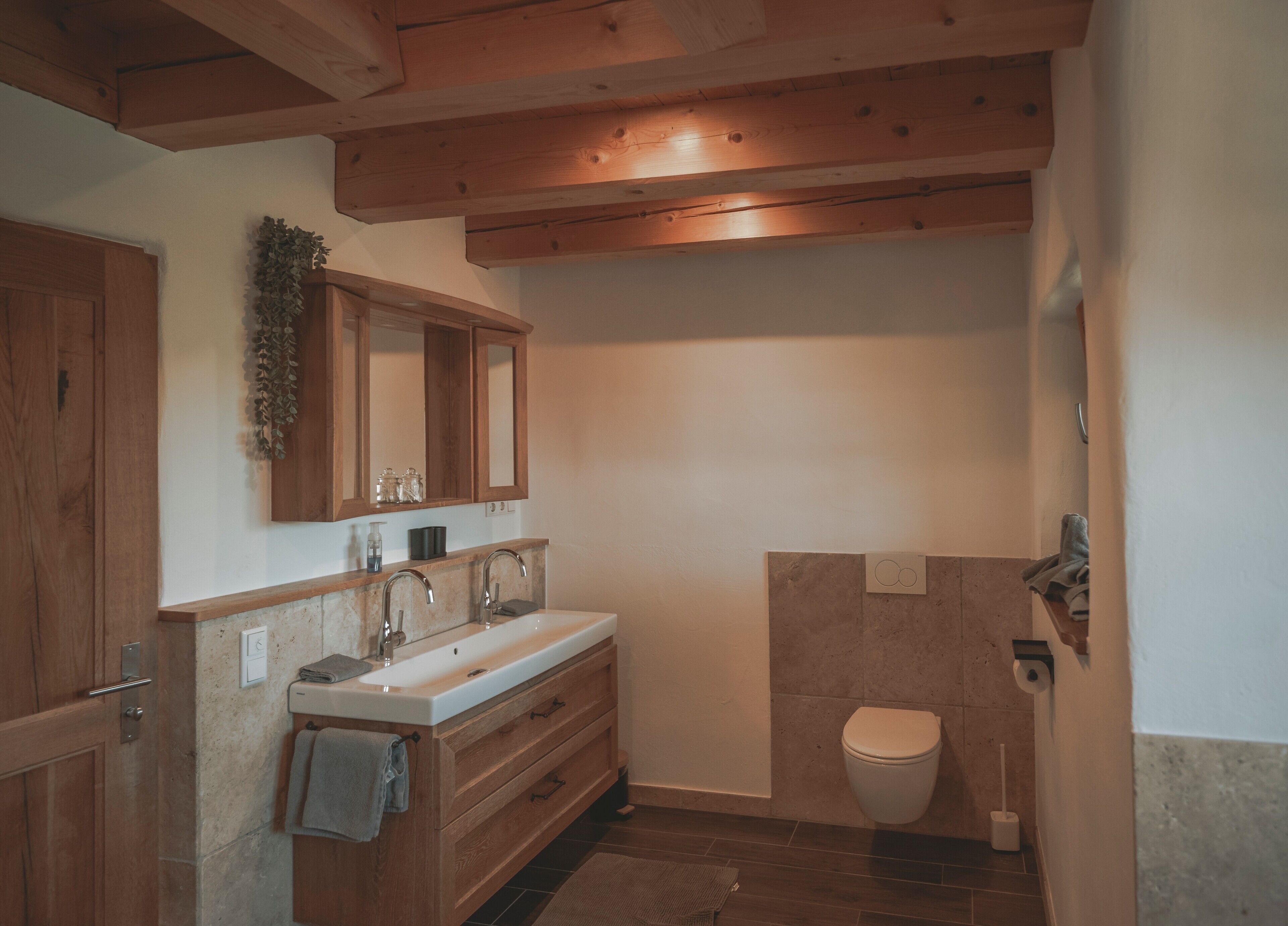 Un bagno con mobili in legno, un lavandino, un water e una zona doccia.
